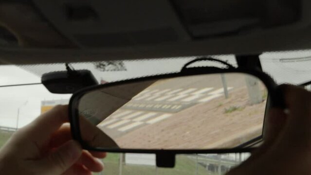 Male hands fine-tuning the rear view mirror inside a vehicle, taking a moment for a careful and attentive pre-drive check