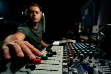 A close-up of a mixing console device used by a man working as professional sound engineer in a...