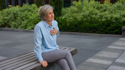 Caucasian senior old mature woman sick unhealthy businesswoman in city bad feeling pain in chest...