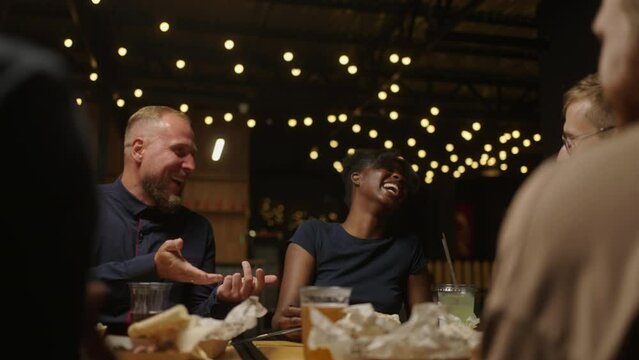 Joyful Black Woman Spending Weekend Evening With Friends In Restaurant, Laughing And Having Fun