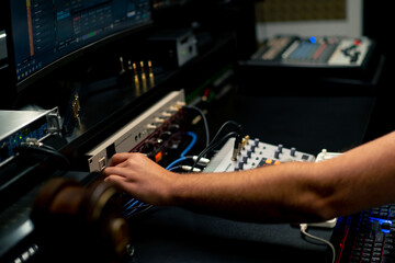 close-up shot of the male hand of a sound engineer switching settings on mixing console for...