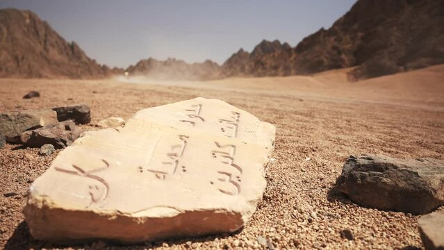 Two atv bikes in the blurred background passing fast by the fragment of the stone slab with arabic script