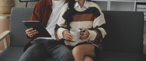 Young woman and young man using laptop while sitting by the sofa at home