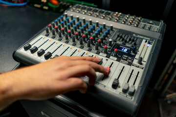close-up shot of the male hand of a sound engineer switching settings on mixing console for...