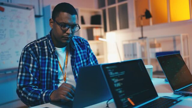 Focused man working as programmer, writing computer code, developing software