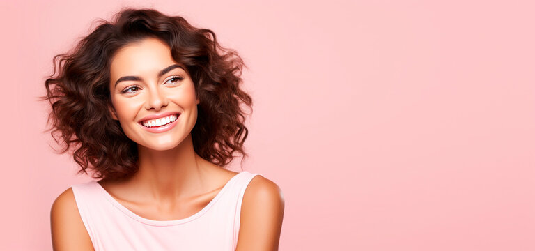 Portrait of young brunette curly woman smiling on pink background while looking right, beauty smile on face, looking natural and charming