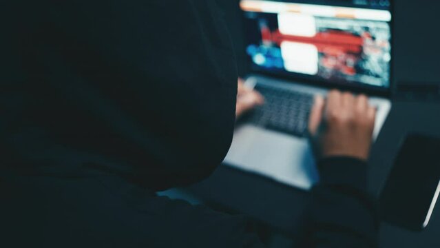 Back view of a hacker copying files, stealing sensitive data, security breach