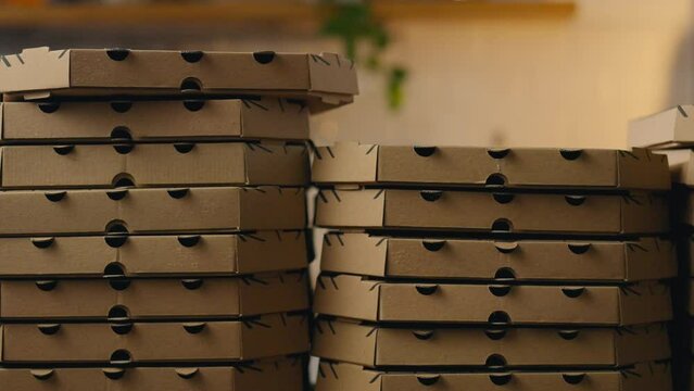 Background from cardboard pizza boxes. smooth camera movement. Large stacks of piles of cardboard boxes for pizza delivery. Pizza baking workshop food delivery to home courier delivery