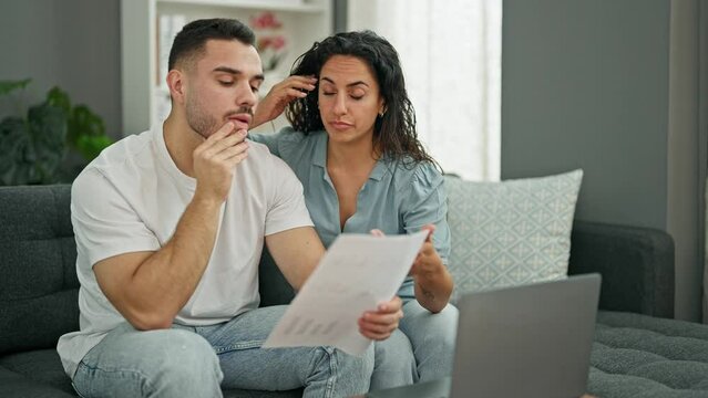 Man and woman couple using laptop reading document looking upset at home