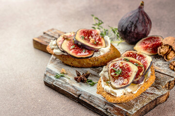 Bruschetta with fresh purple figs, ricotta cheese and honey on a wooden board, place for text, top...