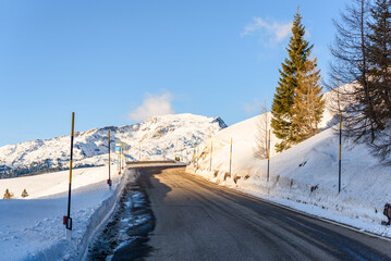 Deserted stretch of a mountain pass road between snowy slopes on a sunny winter day