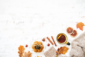 Autumn background. Cup of hot tea, warm sweater, autumn leaves, spices and decorations on white. Flat lay with copy space.