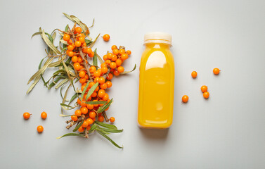Sea buckthorn healthy juicy drink in bottle and branches with leaves and ripe berries top view on...