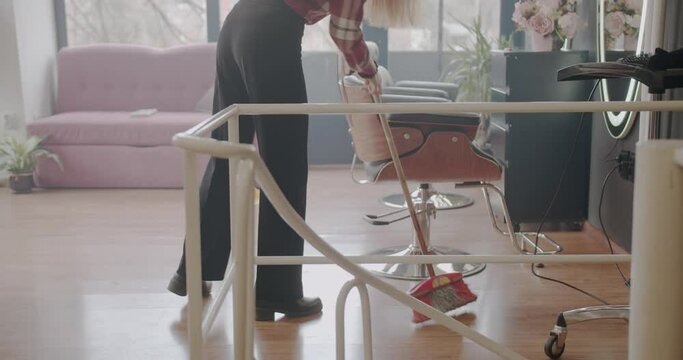 Ginger girl mopping the floor of the hairstyling studio after the haircut, trucking motion