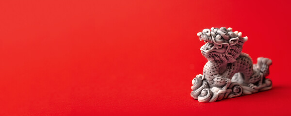 Grey dragon statue on a red background. The symbol of 2024. Happy Chinese New Year.