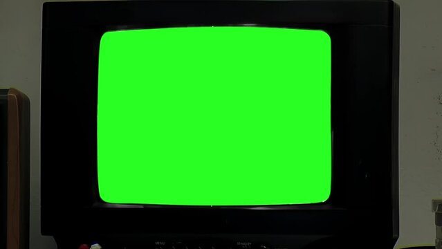 An Old TV Set Green Screen in Dark Room. Close Up. You can replace green screen with the footage or picture you want. You can do it with “Keying” effect in After Effects.
