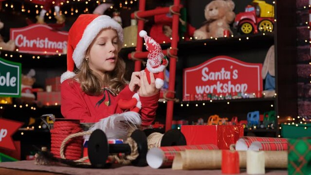 Cute little girl Santa helper Elf packing gifts at studio workshop, slow motion. winter holidays and New Year celebration concept