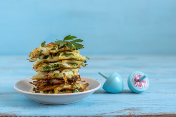 Cabbage fritters or latkes for Jewish holiday Hanukkah on blue wooden background.