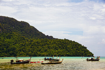 typical Thai fisher boats in front of a green mountain