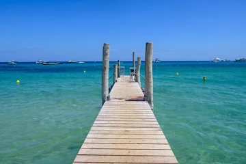 Fotobehang Wooden pier and crystal clear blue water of legendary Pampelonne beach near Saint-Tropez, summer vacation on French Riviera, France © barmalini
