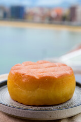 Spanish hard smoked cow cheese from Pria, Asturias, served outdoor with view on San Lorenzo beach in Gijon