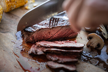 closeup of knife cutting Juicy steak medium rare beef on wooden board 