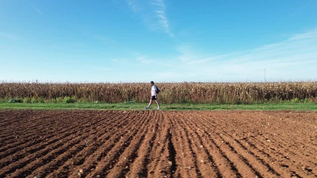Homme qui marche sur un chemin au milieu des champs - vu depuis un drone - vu de cot&eacute; - pratique de la randonn&eacute;e