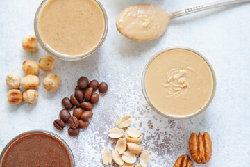 Homemade nuts butter in a glass jars with various nuts.
