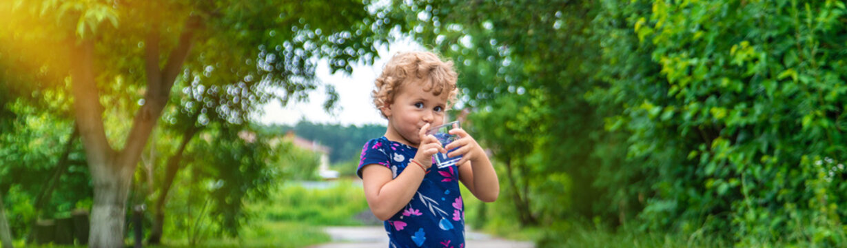 A child drinks water from a glass. Selective focus.