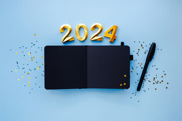 New Year empty goals, plans 2024 concept with black notebook and pen. Flat lay style. Christmas...