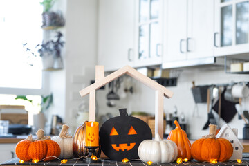 Decor of white classic kitchen with pumpkins, garlands, jack latern for Halloween and harvest with...