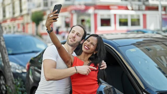 Beautiful couple make selfie by smartphone standing by car at street