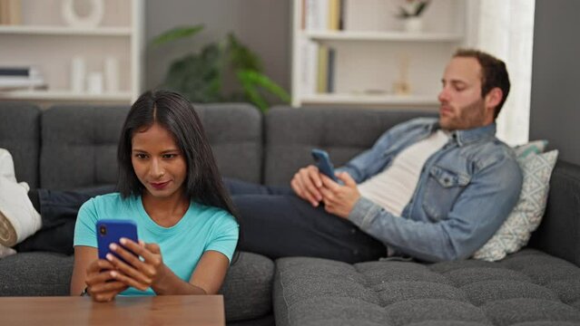 Beautiful couple using smartphones at home