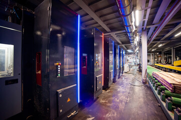 Large woodworking factory with modern industrial equipment and stacks of processed timber,...