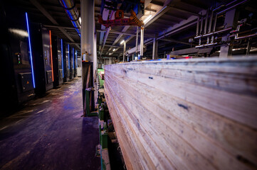 Large woodworking factory with modern industrial equipment and stacks of processed timber,...