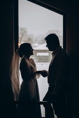 Silhouette of the bride and groom on the window. Winter time