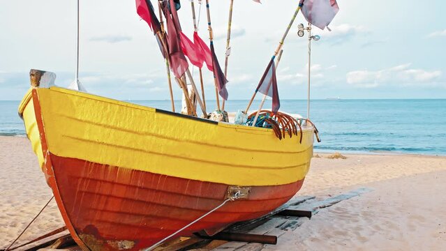 Undecked Handliner Fishing Vessel with Net Flags and Rusty Hooks Purse Sein Equipment Parked on Beach Sand at Seashore on Calm Day