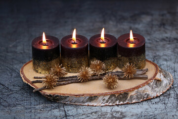 Vierter Advent: Vier brennenden Kerze mit Weihnachtsdekoration vor dunkelm Hintergrund. 