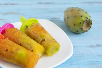 Frozen Opuntia fruits on ceramic plate over wooden background.
