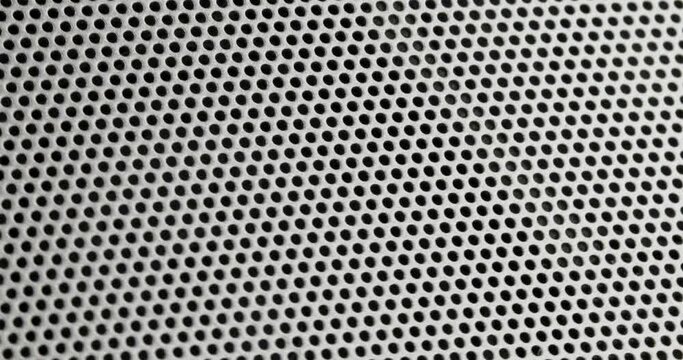 Steel Grill Grid pattern background - silver metallic speaker grill with round black holes flies under camera.  Technology or industrial background.