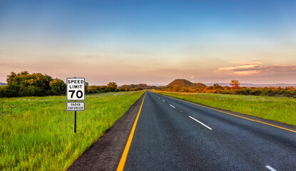 speed limit 70, enforced by radar, road sign marking on the side of the road warning drivers to...