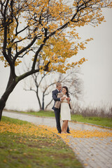 Romantic autumn wedding. Couple of young man and woman on autumn walk outdoors. Two lovers in a fall park. Love and tender touch. Autumn wedding. Rainy autumn wedding day. Yellow fall. 