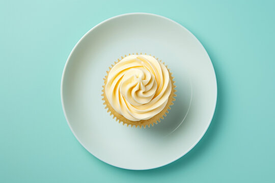 Butter cupcake on plate, on solid color background, top view
