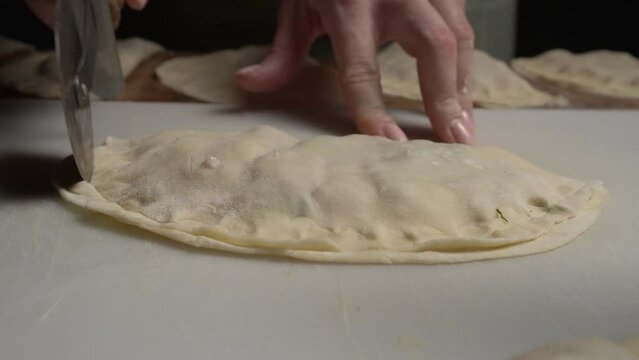 The girl trims the edges of the dough