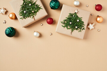 DIY homemade Christmas gifts with fir branches and colorful baubles on beige background. Flat lay, top view.
