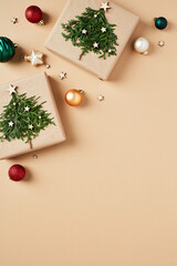 Homemade Christmas gift boxes with fir branches and baubles on beige background. DIY Xmas presents, vintage style.