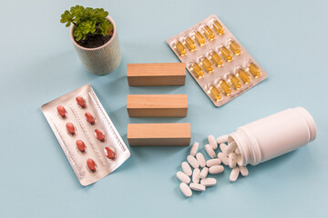 Transparent capsules with fish oil, blisters, capsules and wooden cubes on a blue background. Omega...