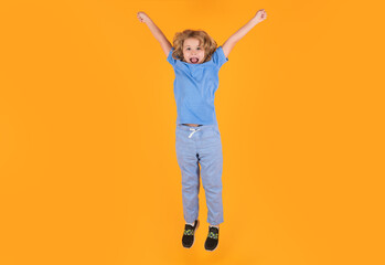 Funny boy jumping. Kid boy 8-9 years old in t-shirt jump isolated on yellow background. Childhood lifestyle concept. Mock up copy space. Kid having fun, jumping.