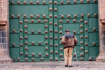 old man praying in front of Cusco Cathedral.