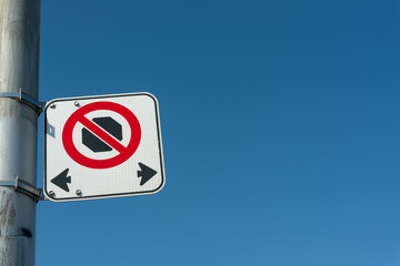 no stopping at any time with two arrows fastened to a utility pole on a clear blue sky